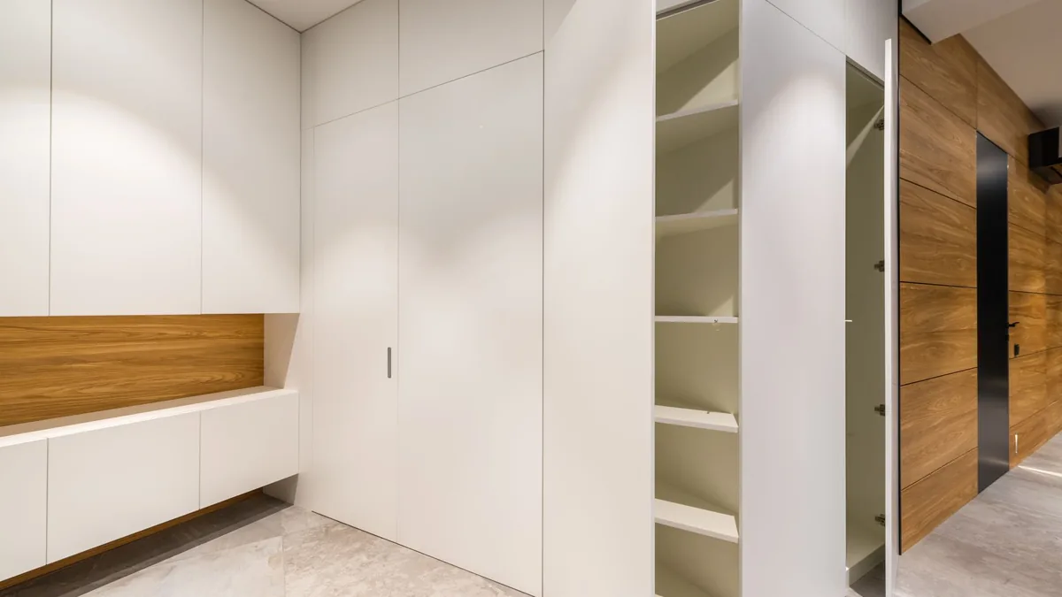 Armario empotrado con puertas blancas lacadas, una de ellas entreabierta mostrando las baldas interiores.